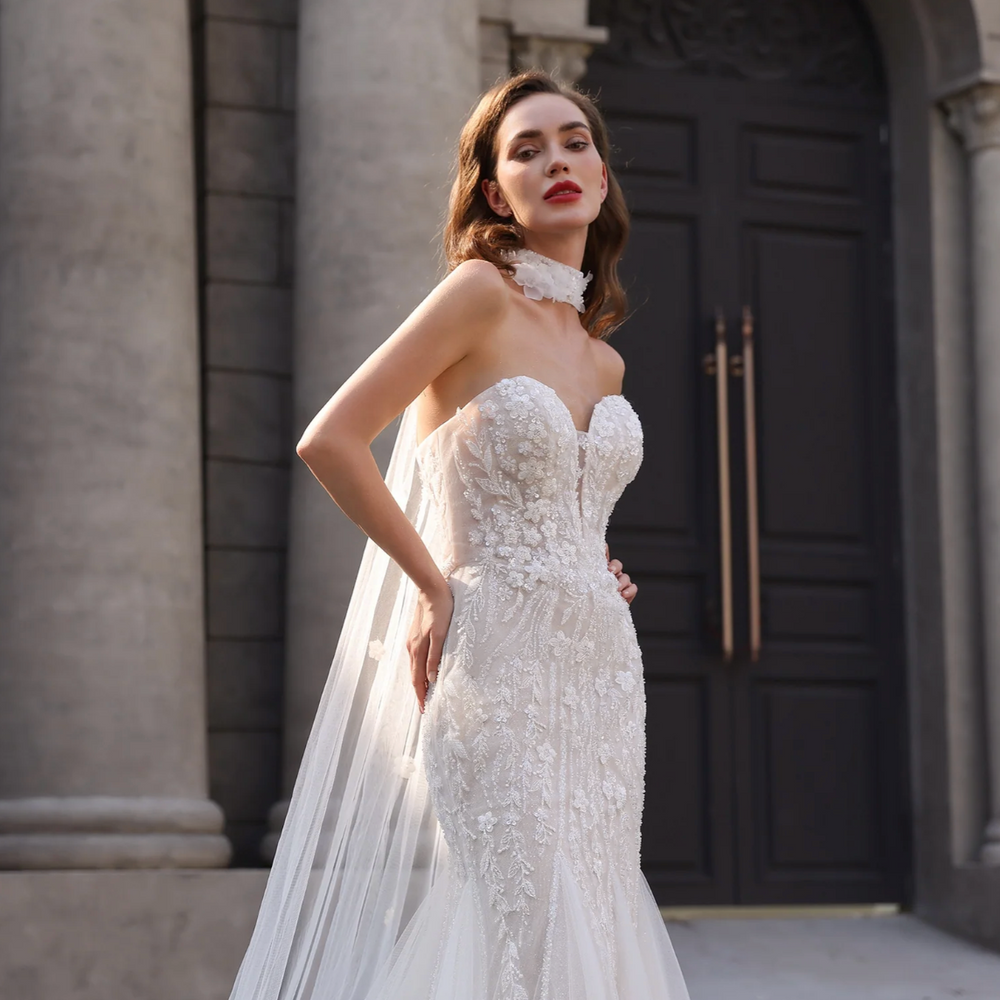 
                      
                        Woman in a white wedding dress standing in front of a classical building entrance.
                      
                    