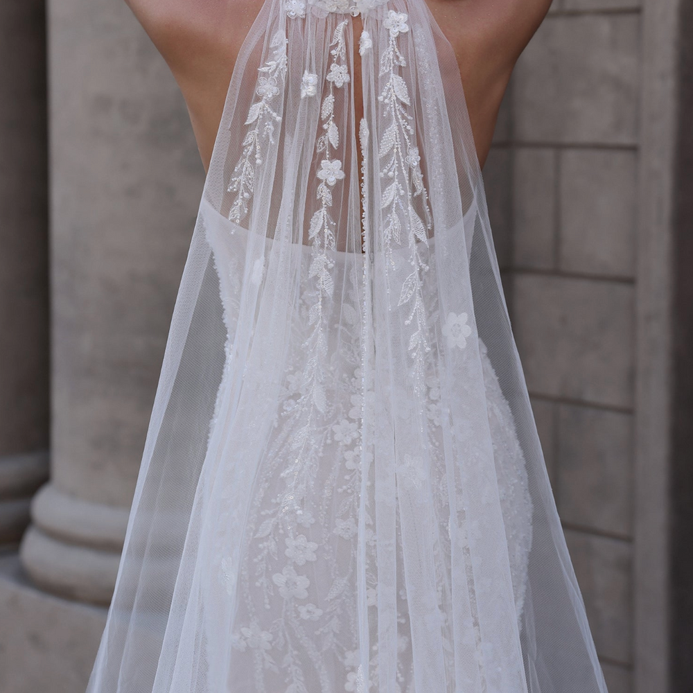 
                      
                        White lace dress with a floral back design, worn by a person, with 'Ludyne Yuced' branding.
                      
                    