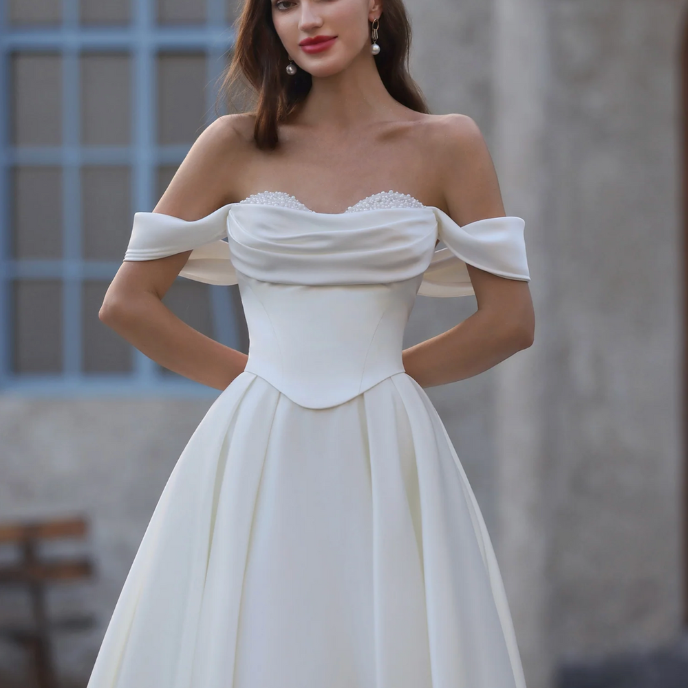 
                      
                        Woman wearing a white off-shoulder gown with a blurred background
                      
                    