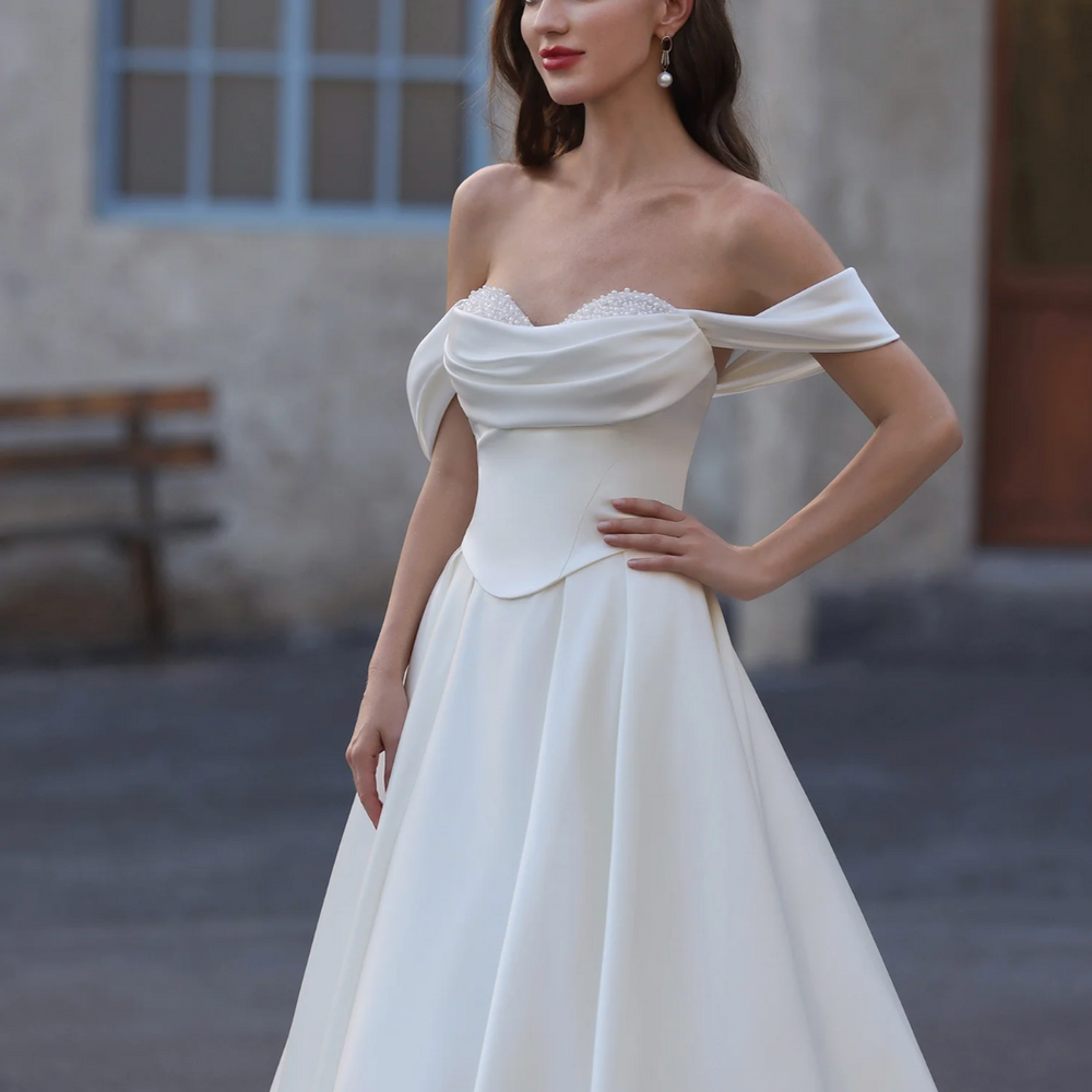 
                      
                        Woman wearing a white off-shoulder gown with a blurred background
                      
                    