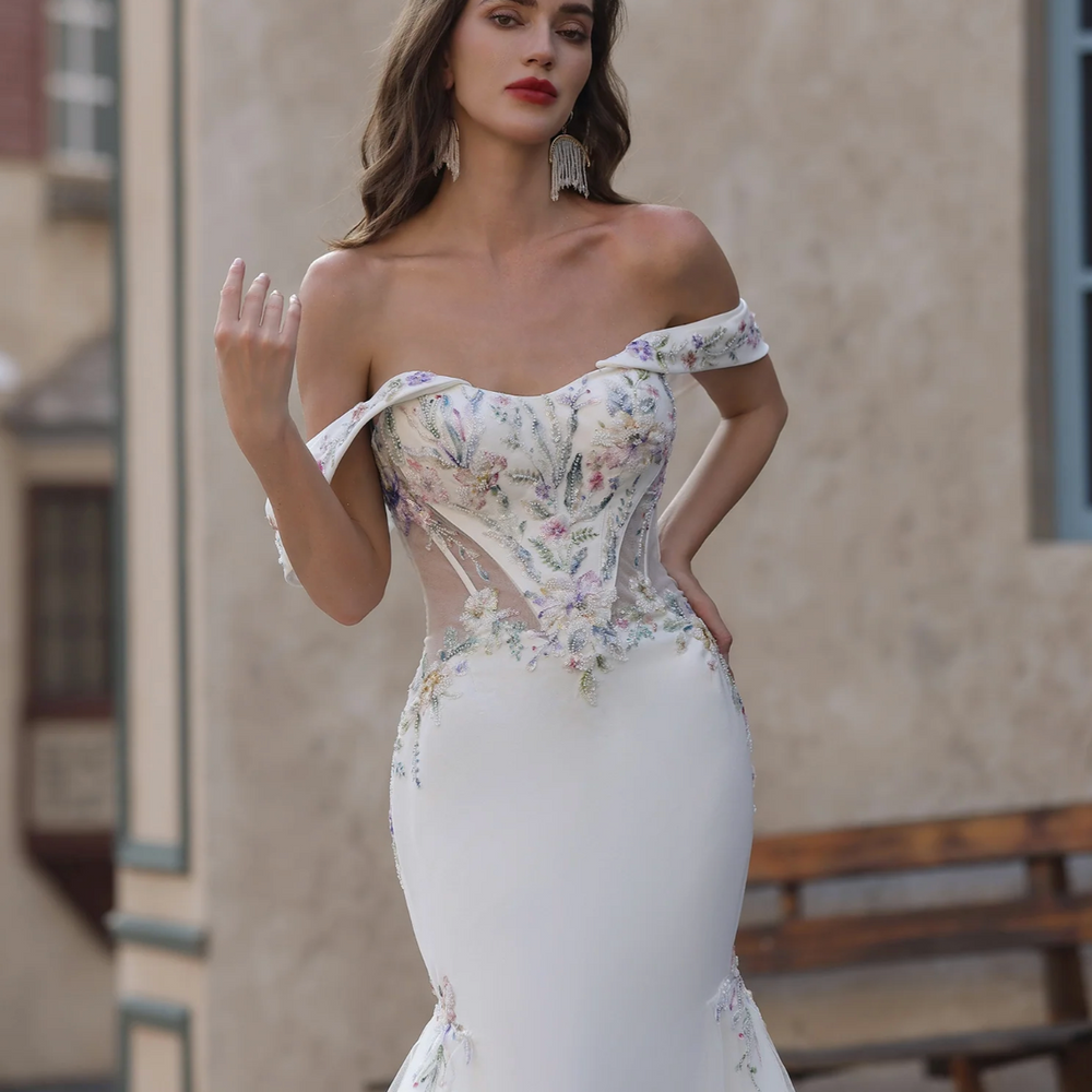 
                      
                        Woman wearing a floral off-shoulder wedding dress with 'Ludyne Yuceed' branding.
                      
                    