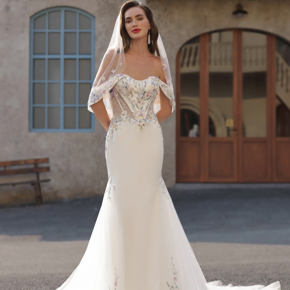 
                      
                        Woman in a white wedding dress with a veil standing in front of a building.
                      
                    