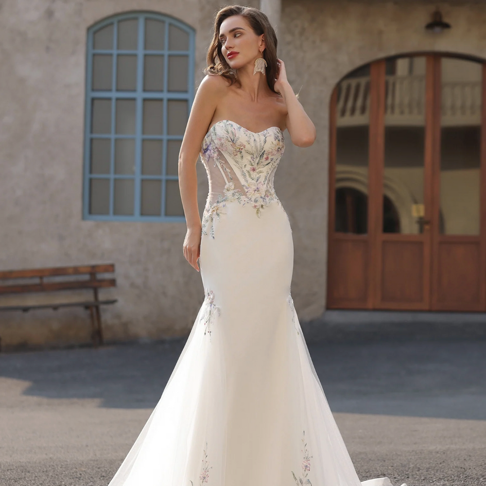 
                      
                        Woman in a white wedding dress standing outdoors with a building in the background
                      
                    