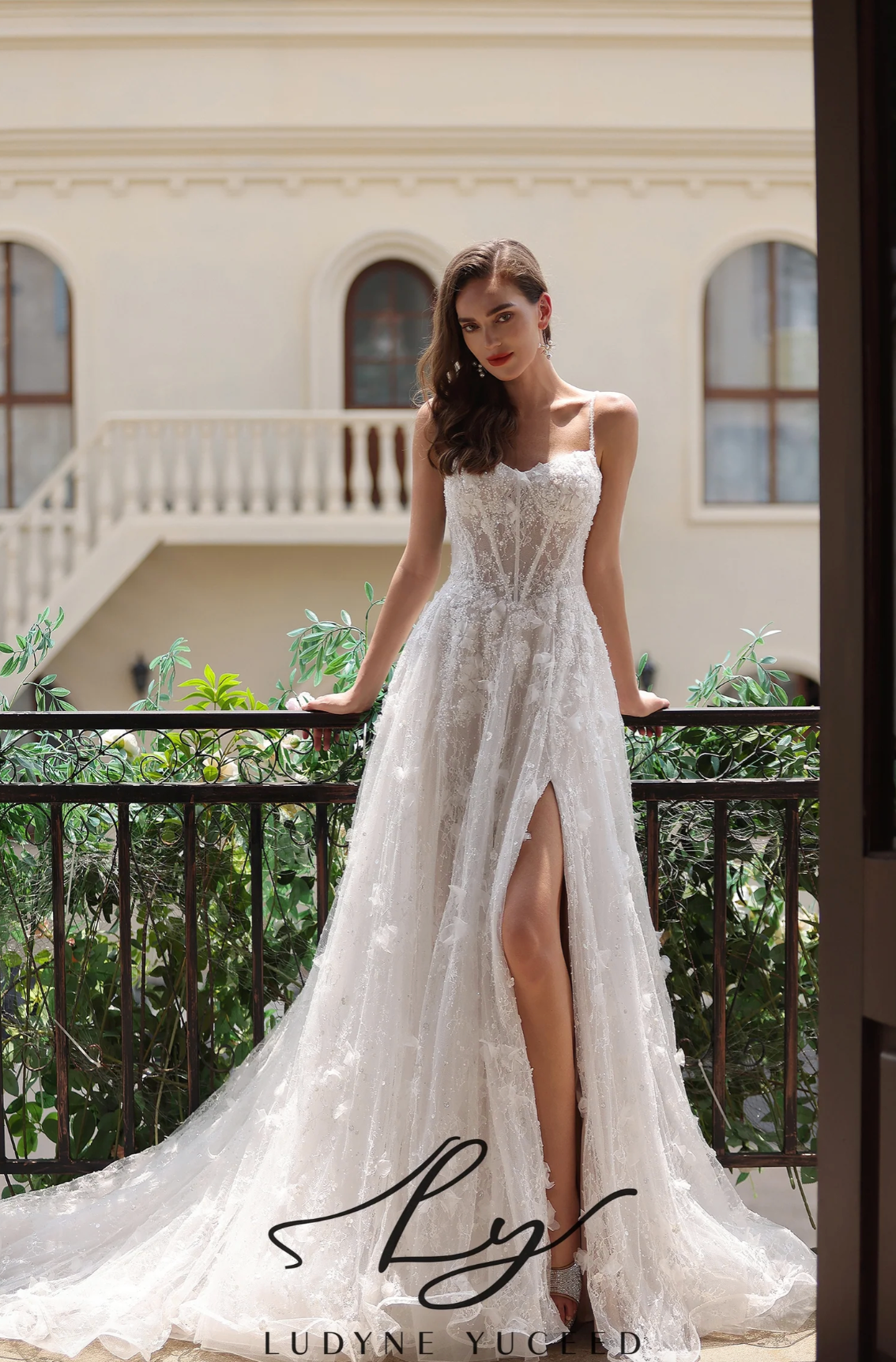 Romantic floral lace wedding gown with a high slit, spaghetti straps, and a flowing train, showcased outdoors.