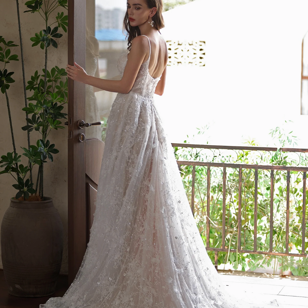 Elegant bride in romantic floral lace wedding gown with a train, showcasing a modern and ethereal style.