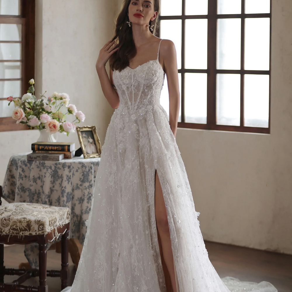 
                      
                        Romantic floral lace wedding gown with high slit, spaghetti straps, and sweetheart neckline in elegant indoor setting.
                      
                    