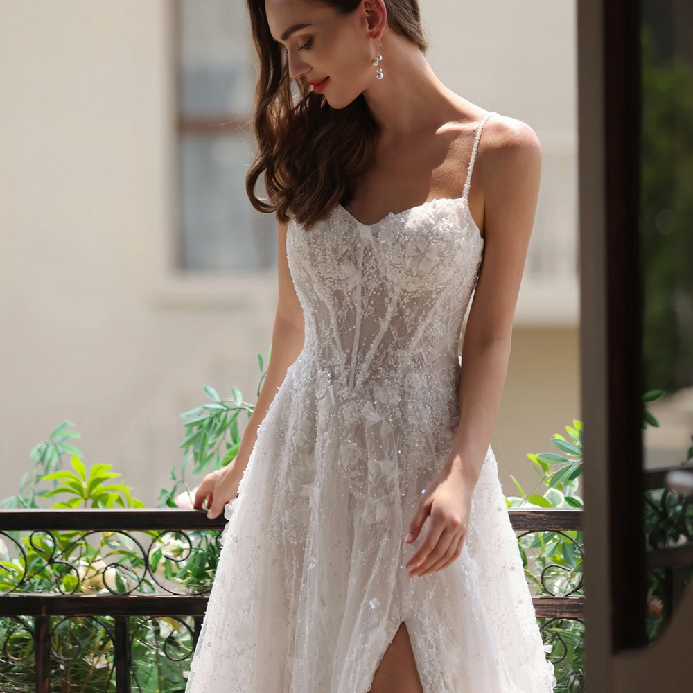 
                      
                        Romantic floral lace wedding gown with a high slit, spaghetti straps, and a sweetheart neckline, elegantly displayed outdoors.
                      
                    