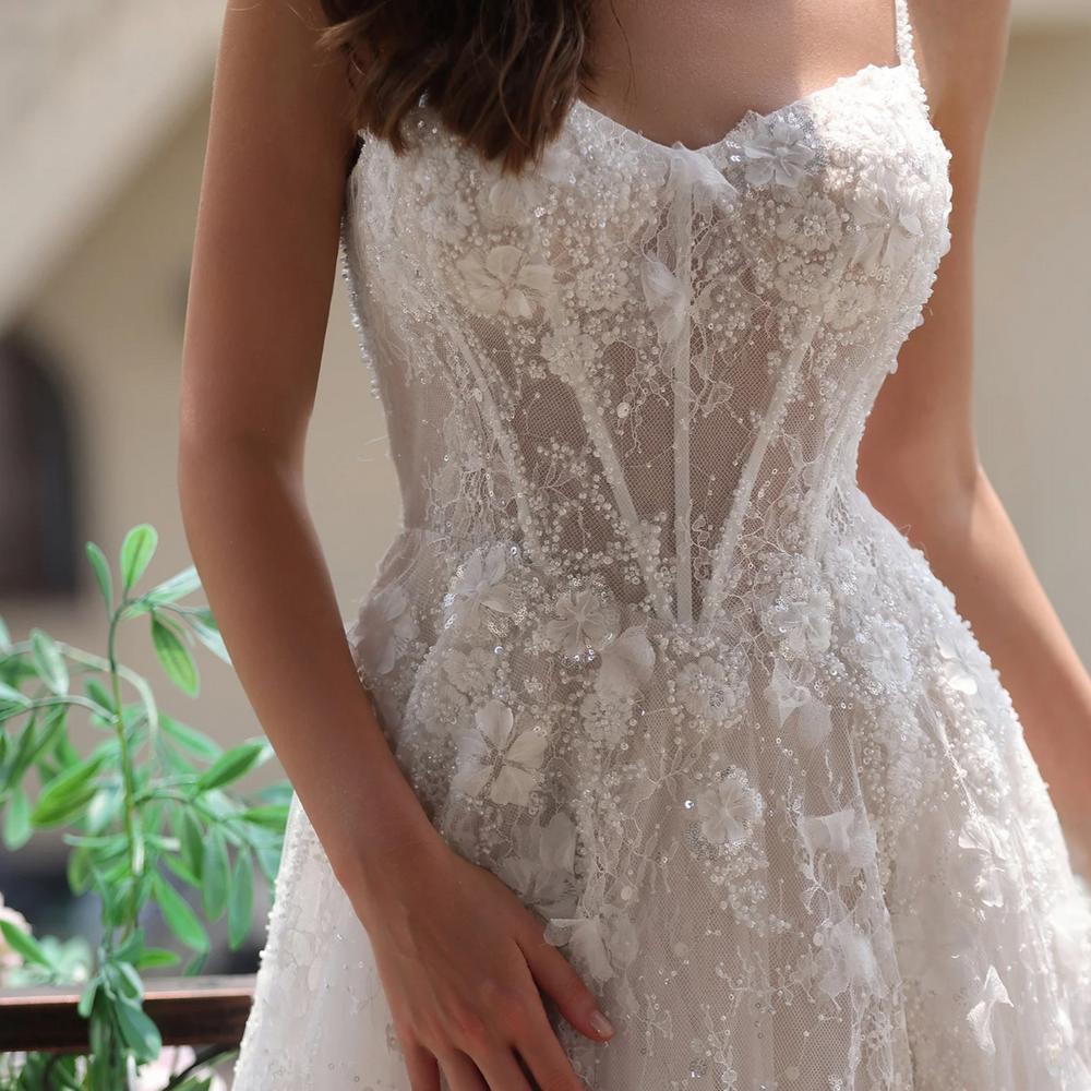 
                      
                        Close-up of a romantic floral lace wedding gown with delicate spaghetti straps and intricate lace details.
                      
                    