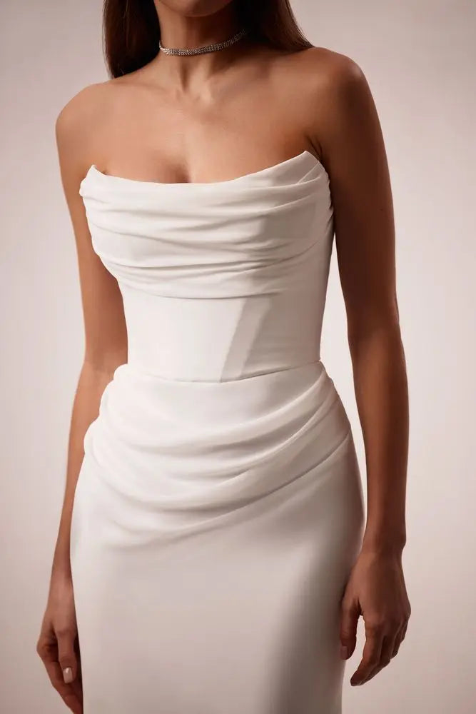 
                      
                        Woman wearing a strapless white wedding dress on a plain background
                      
                    