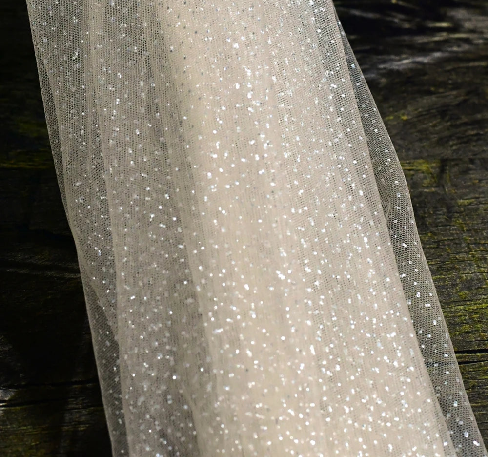 
                      
                        Close-up of a glittery fabric with a dark wooden background
                      
                    