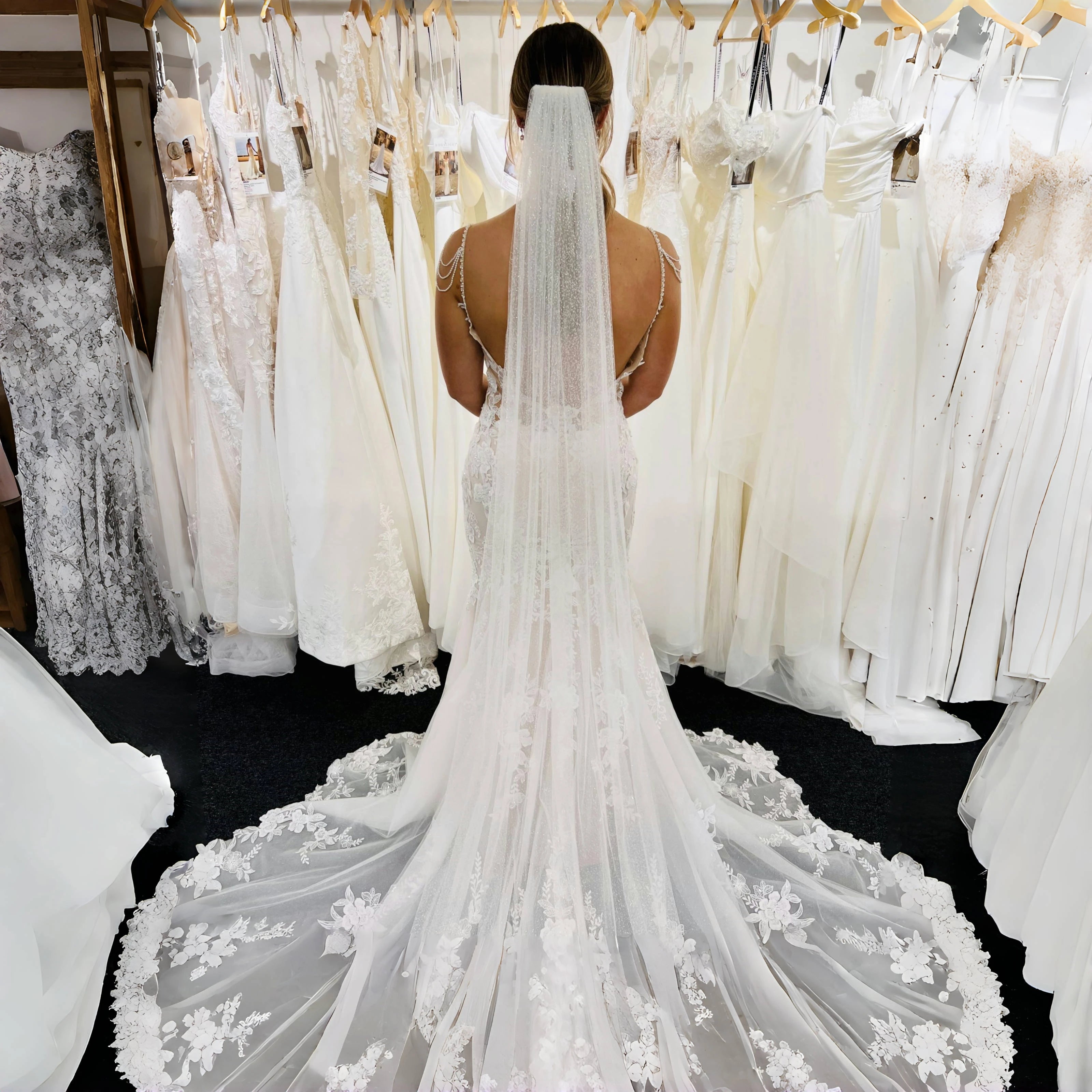 Person wearing a white wedding dress with a veil in a bridal shop.