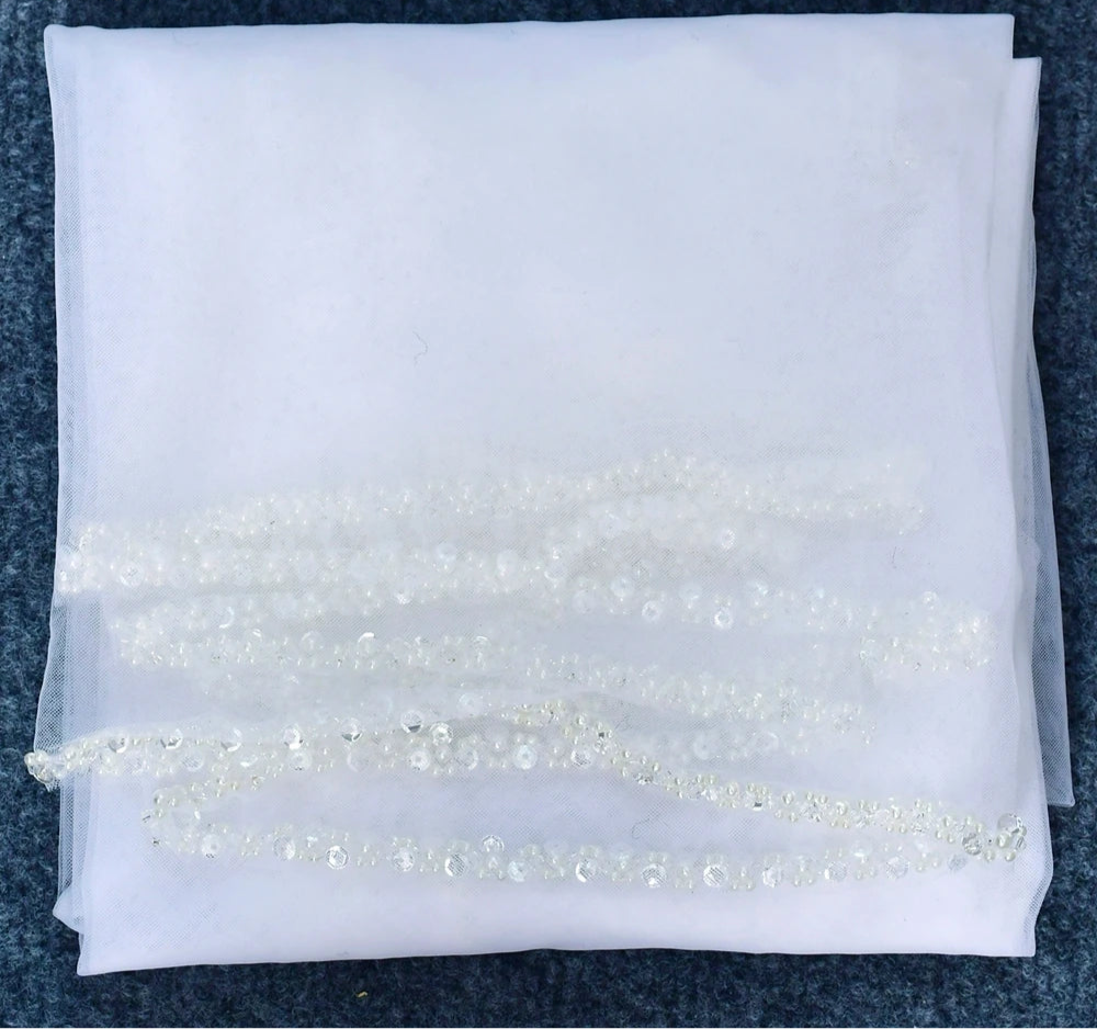
                      
                        White fabric with decorative beads on a dark background
                      
                    