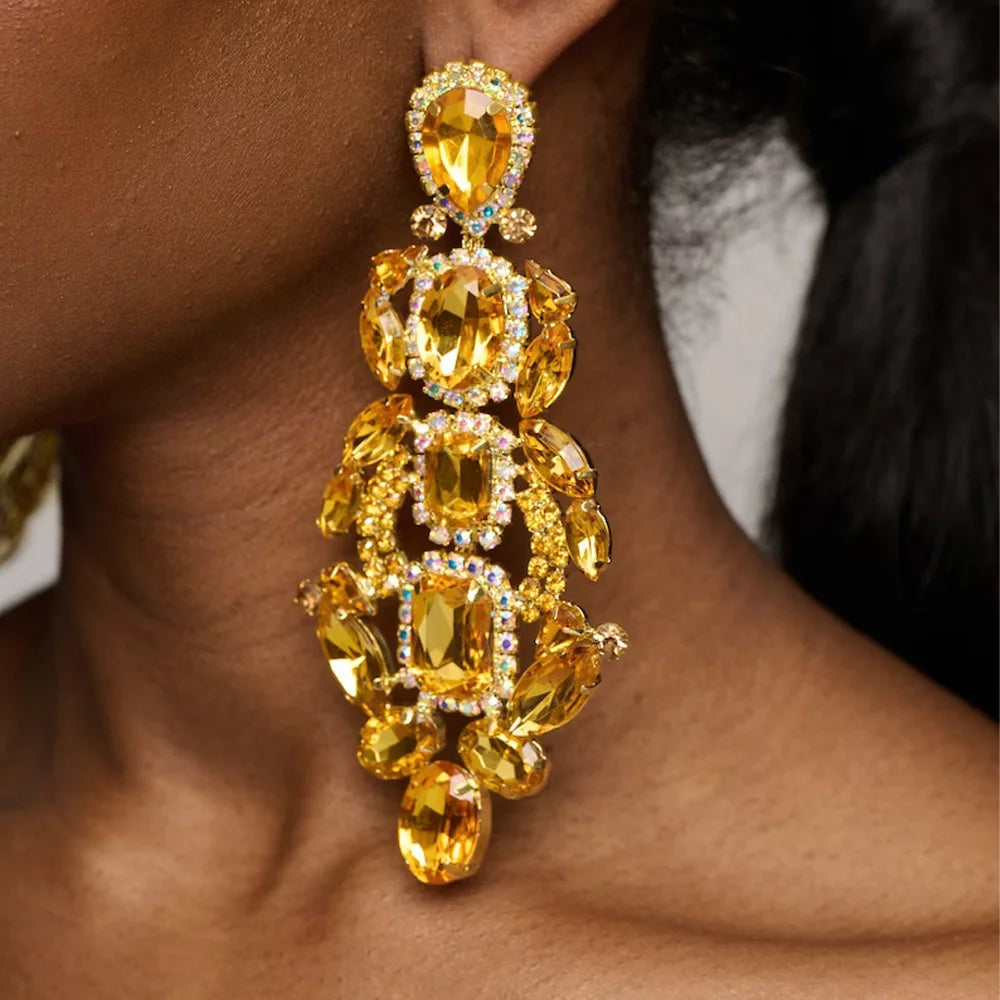 Close-up of a gold earring with yellow gemstones on a person's ear.